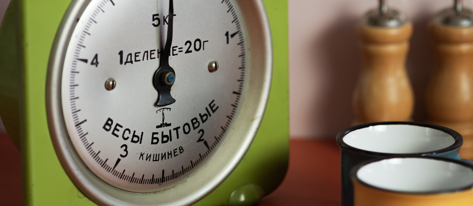 A retro green kitchen scale on a wooden counter