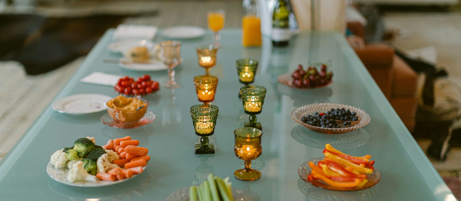 A long table set with appetizers, glasses and candles for a gathering