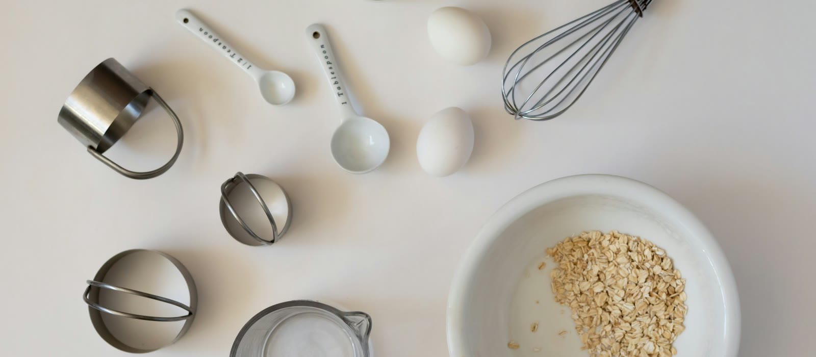 Baking ingredients and measuring tools laid out on a white surface