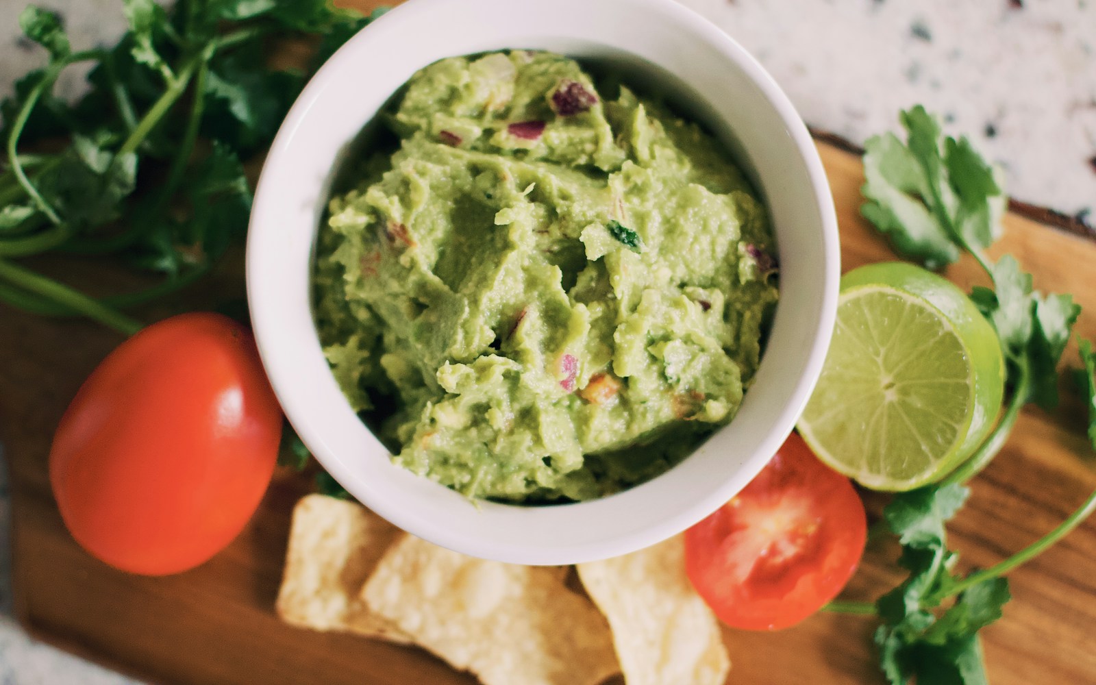 A bowl of chunky guacamole with a green olive oil drizzle and lime