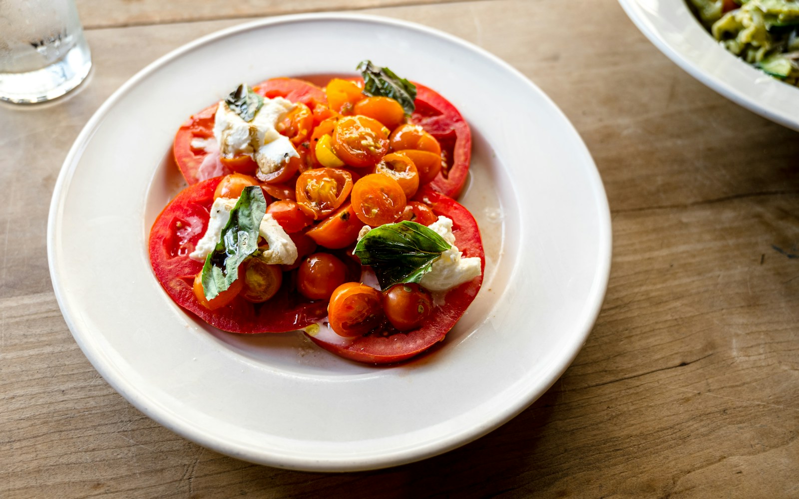 Sliced heirloom tomatoes with mozzarella and basil on a white plate