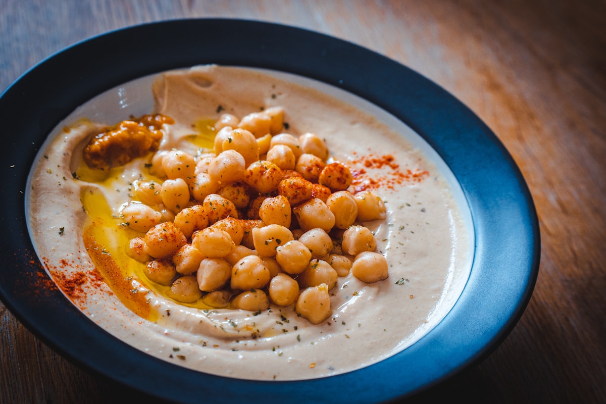 A bowl of hummus swirled with olive oil and dusted with paprika
