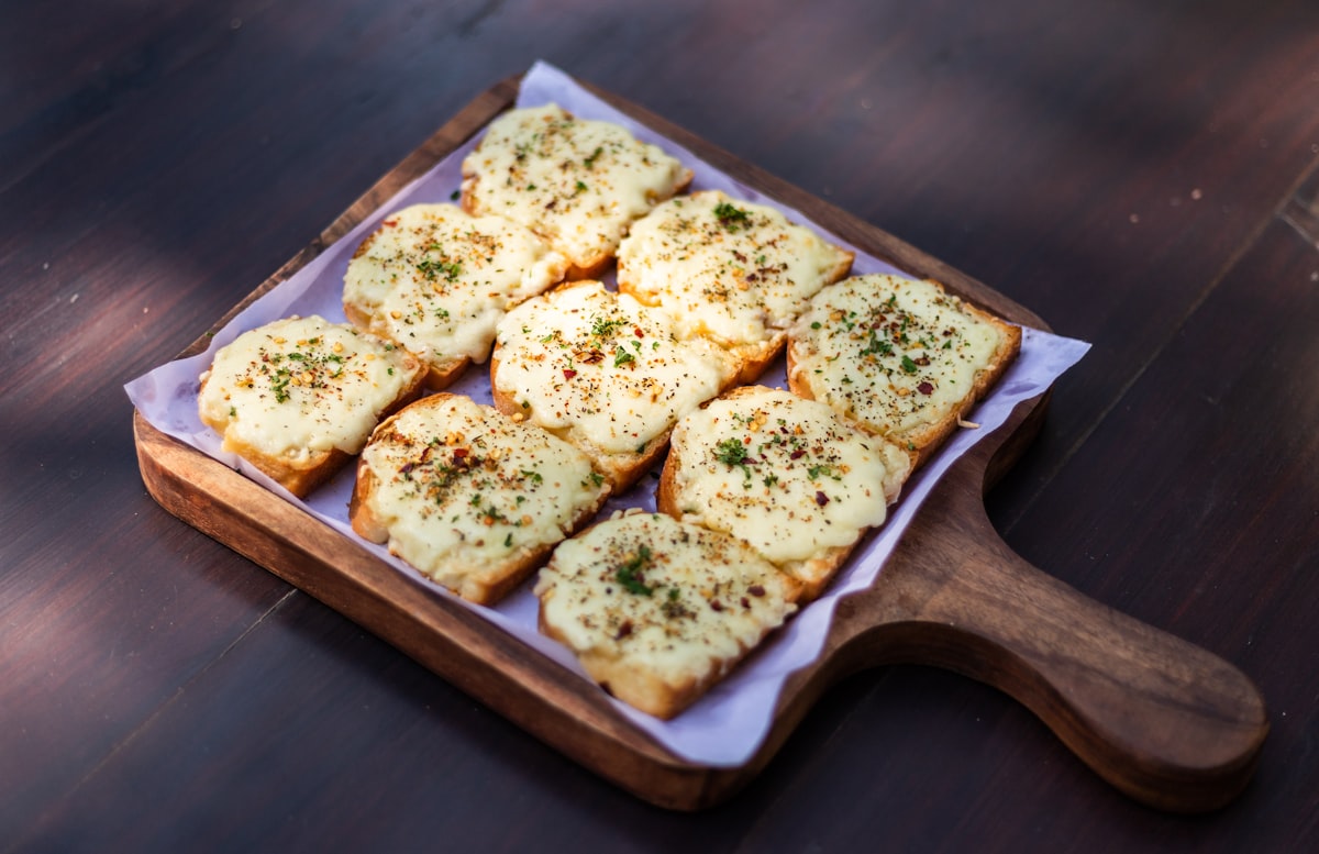 Golden slices of garlic bread with herbs on a wooden board