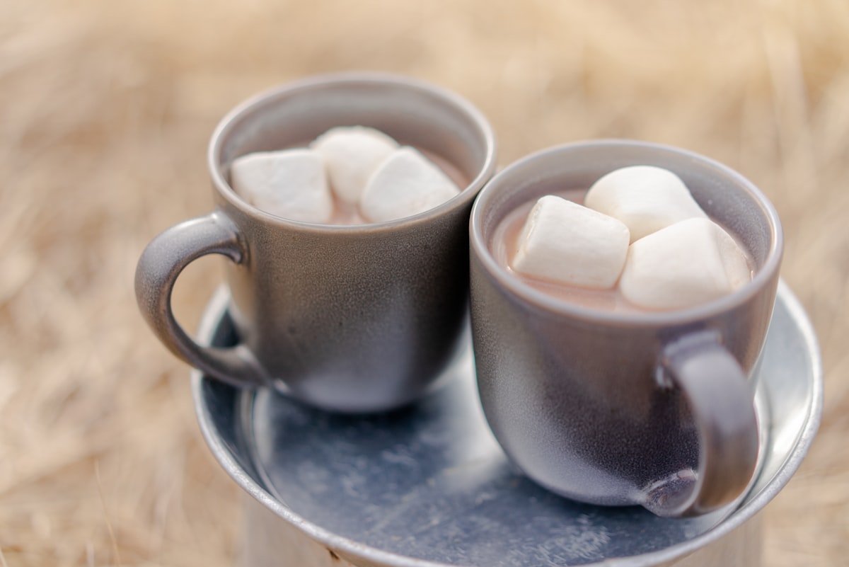 Two mugs of hot chocolate topped with marshmallows on a tray